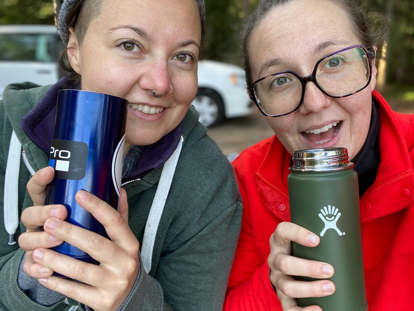 A selfie of Quinn and Emilie with big smiles and coffee thermoses held close